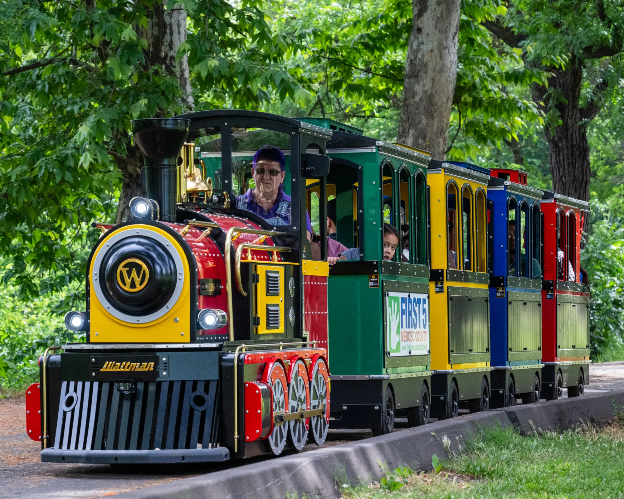 The Kiddieland miniature train carrying riders along a tree-lined track