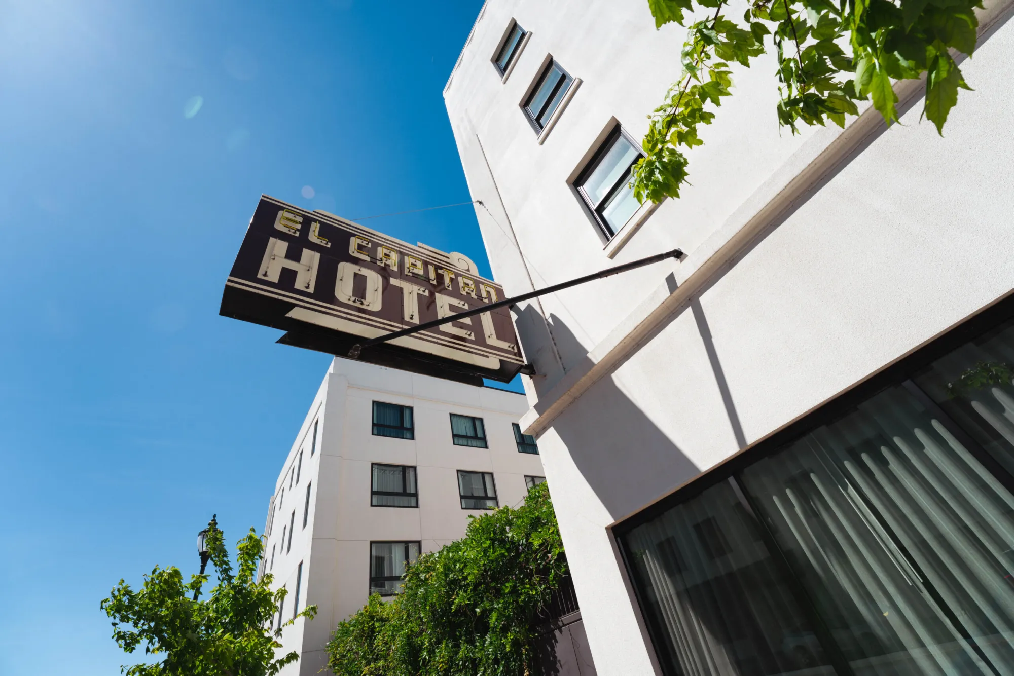 Vintage marquee sign reading "El Capitan Hotel" against a clear blue sky