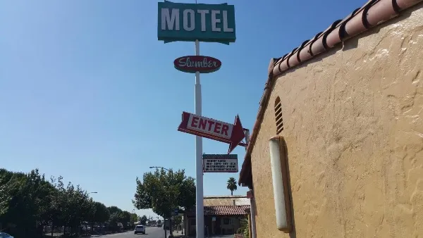 Motel sign and entrance shown from a low angle for the slumber motel