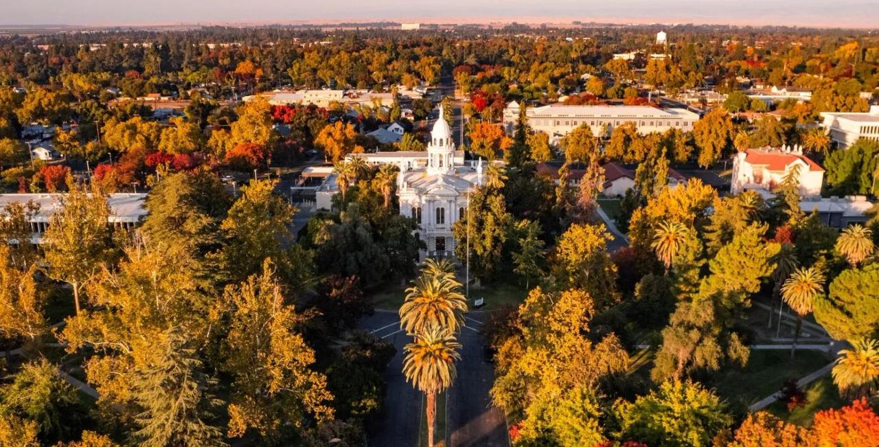 Aerial view of the Merced County Courthouse Museum's white cupola among autumn trees at sunset