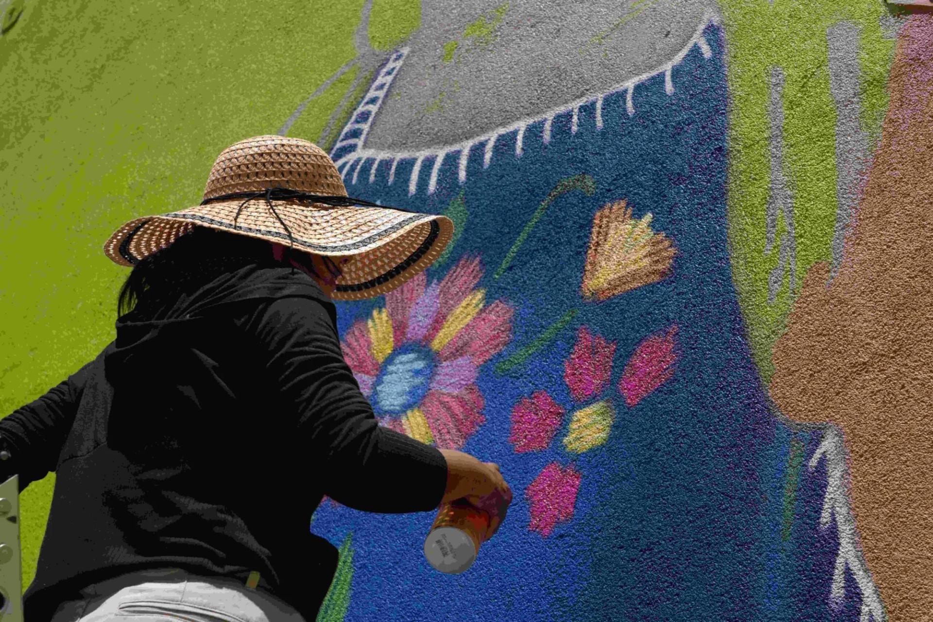 A local community artist working on an outdoor public street art installation, highlighting the creative culture in Merced.